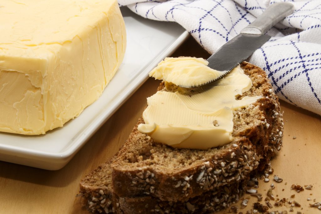 Buttered bread slice on plate with butter dish and cloth