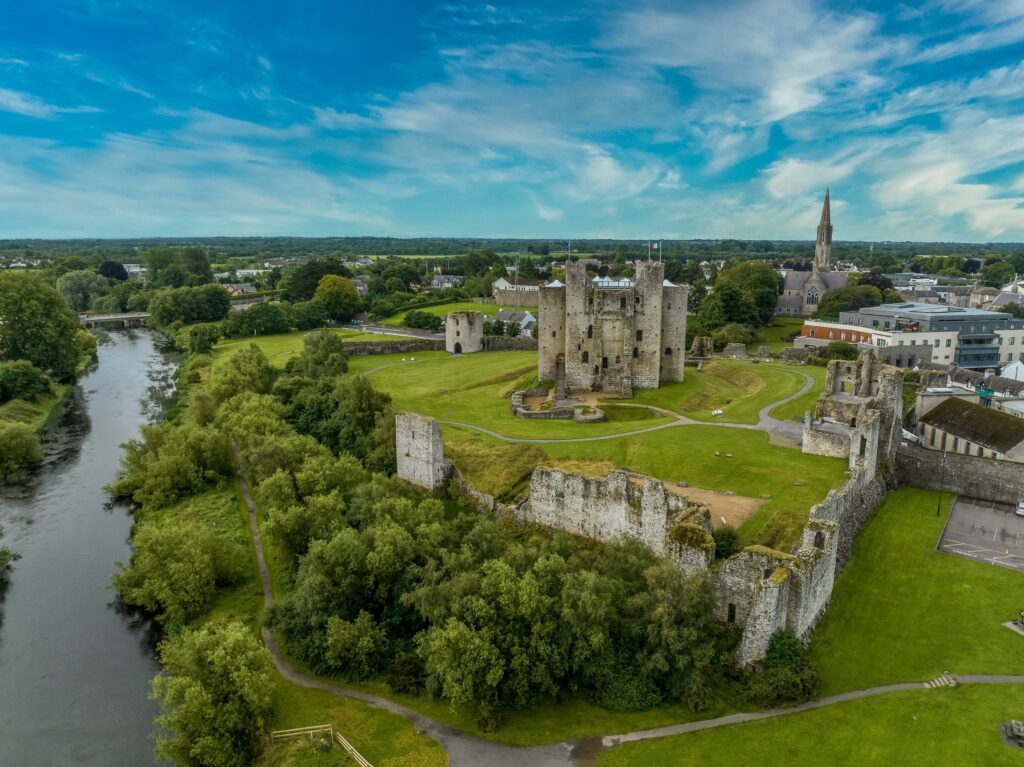 An aerial view of Trim Castle on the River Boyne in County Meath, Ireland. The great Norman keep stands at the centre of a wide green sward: a tall grey limestone tower of cruciform plan with square projecting turrets, empty window openings