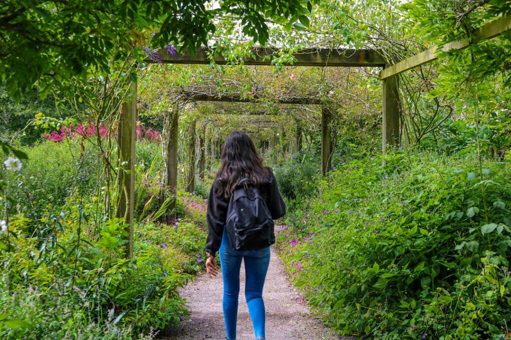 a woman walking down a path in a garden